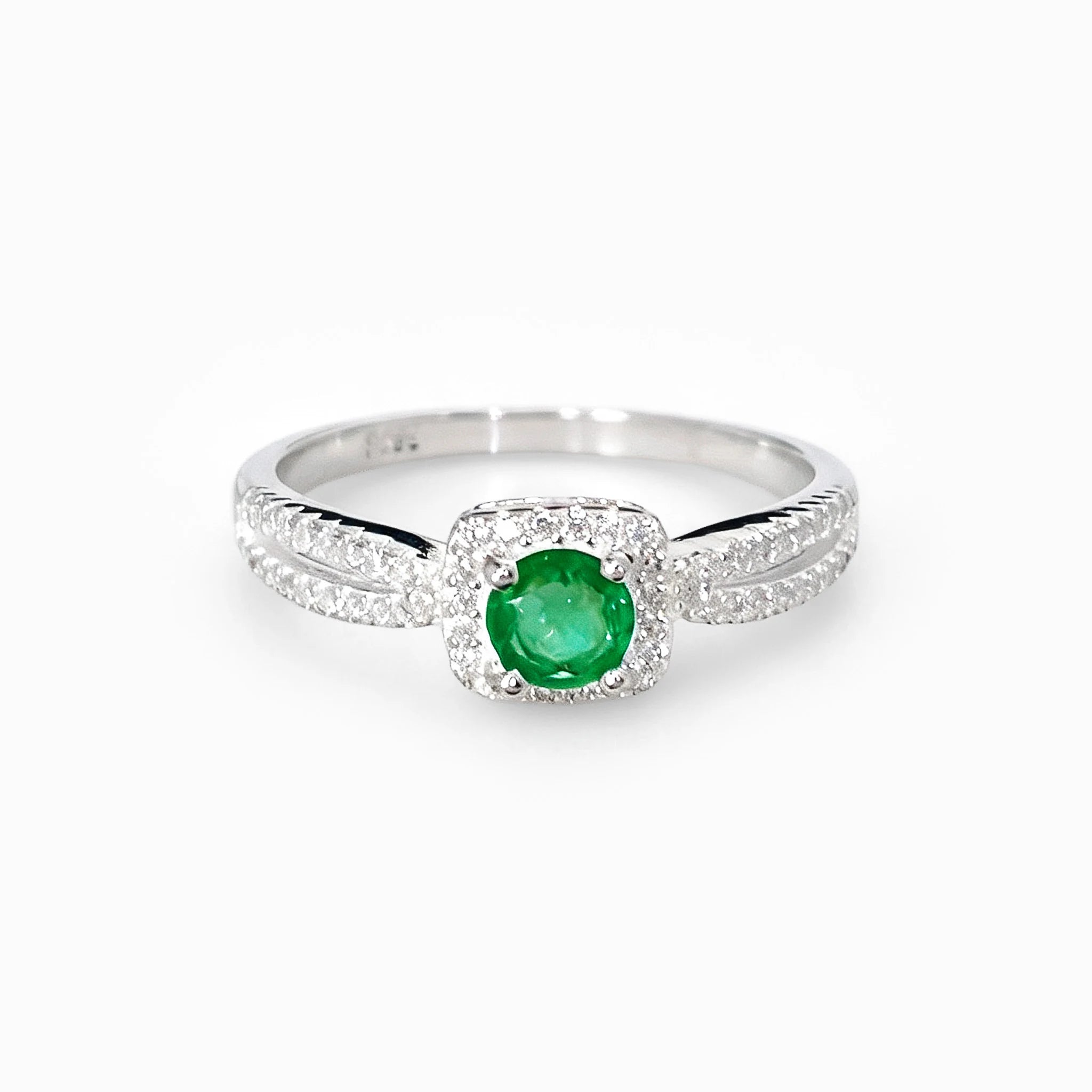 Anillo de halo en plata ley 925 con esmeralda natural central y circones en la banda.