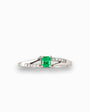 Anillo de plata paladio con esmeralda central de 0.32ct y diamantes laterales en movimiento bypass sobre fondo blanco.