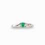 Anillo de plata paladio con esmeralda central de 0.32ct y diamantes laterales en movimiento bypass sobre fondo blanco.