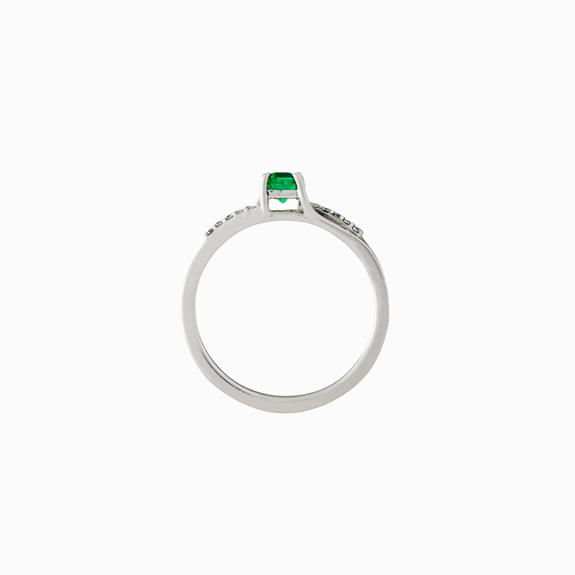  Anillo de plata paladio con esmeralda central de 0.32ct y diamantes laterales en movimiento bypass sobre fondo blanco.
