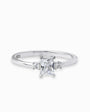 Anillo solitario en Plata Ley 925 talla 8 con un cirón central transparente de corte rectangular y dos piedras redondas laterales.