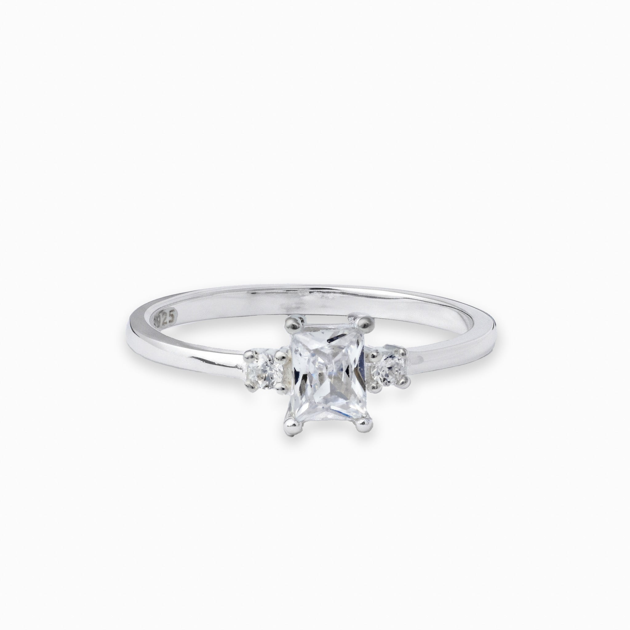 Anillo solitario en Plata Ley 925 talla 8 con un cirón central transparente de corte rectangular y dos piedras redondas laterales.