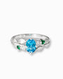 Anillo botánico de Joyería Esterlina en Plata Ley 925 con topacio azul ovalado y esmeraldas laterales.