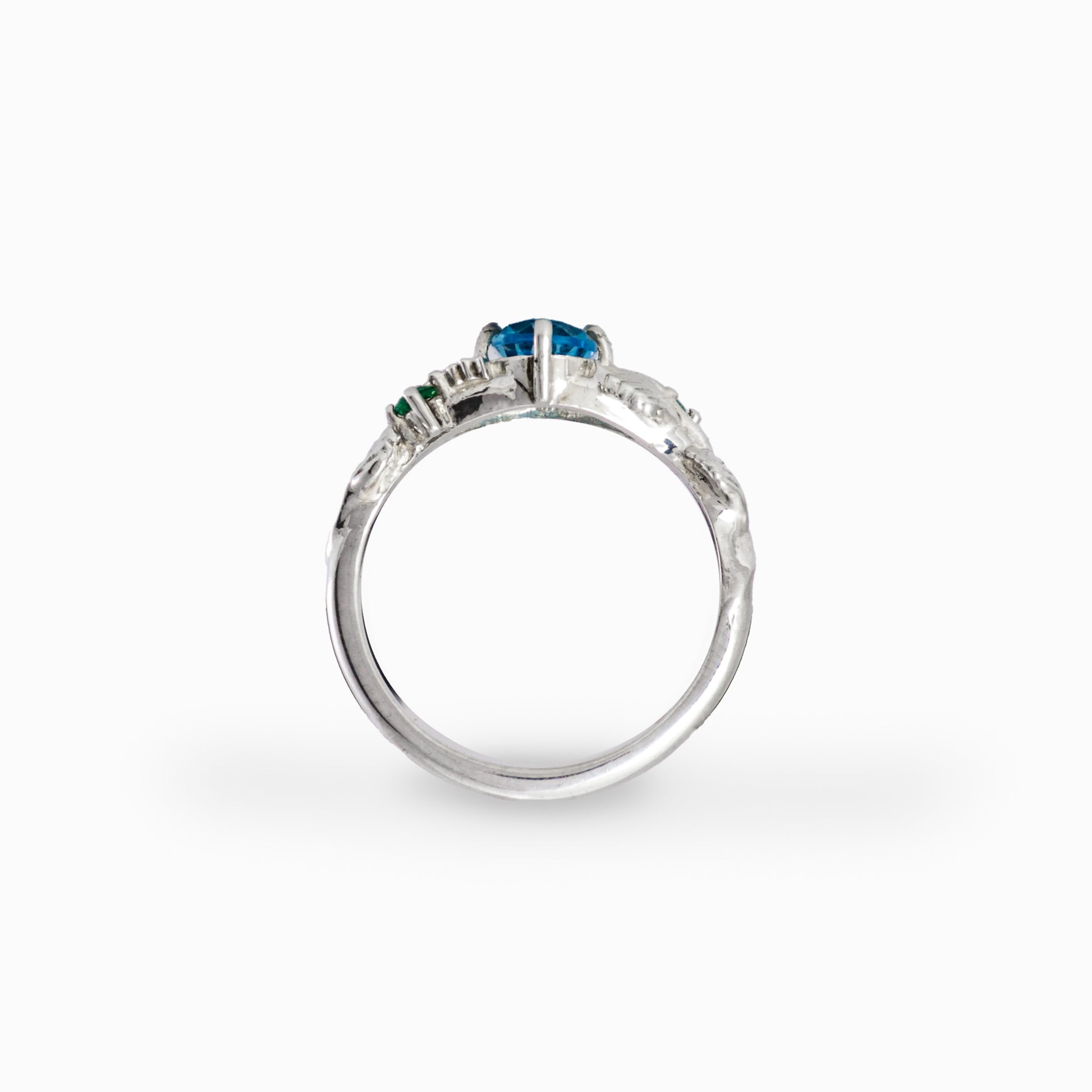 Anillo botánico de Joyería Esterlina en Plata Ley 925 con topacio azul ovalado y esmeraldas laterales.