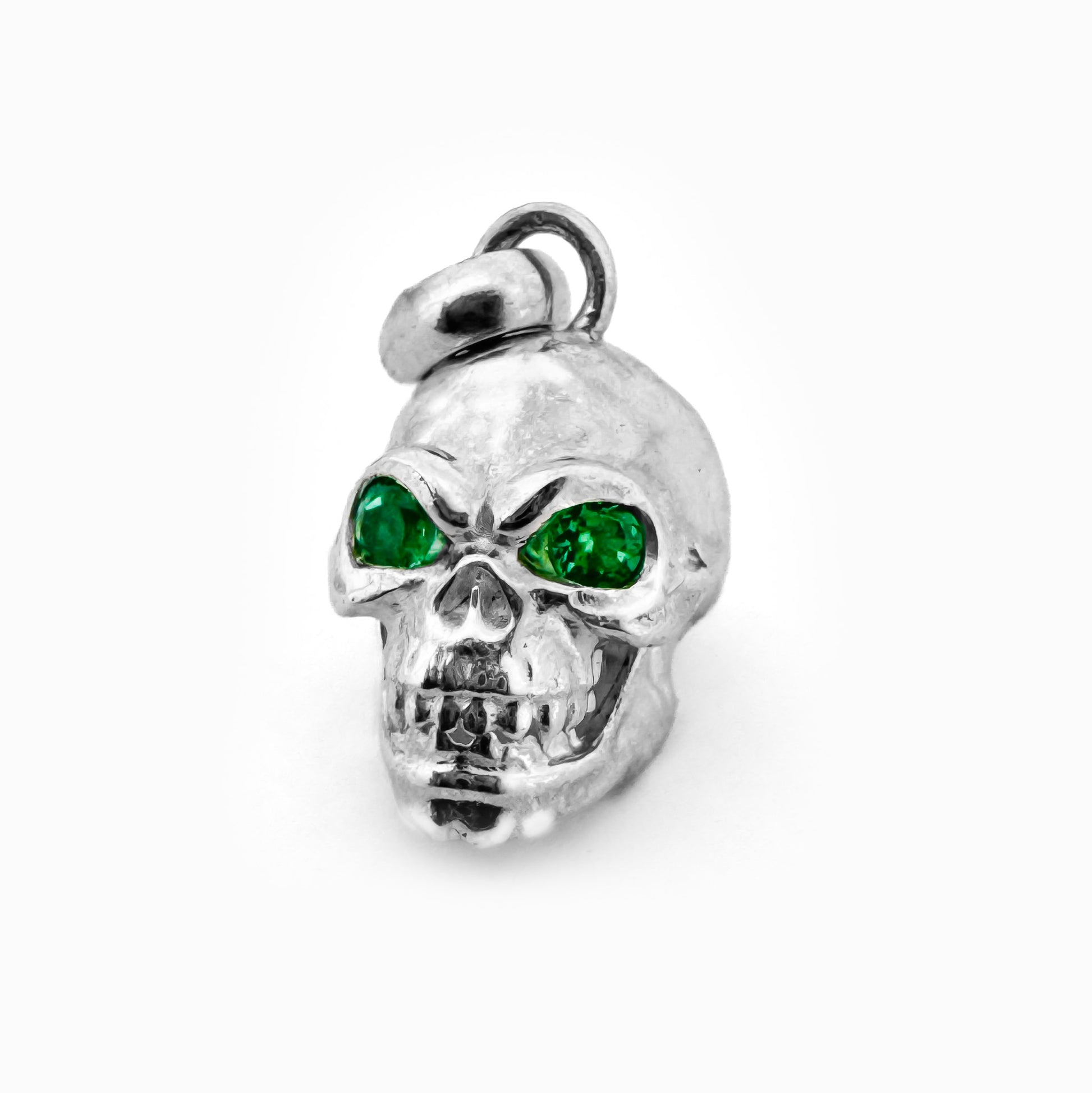 Dije tridimensional de calavera en Plata Ley 925 con dos esmeraldas naturales brillantes engastadas en los ojos.