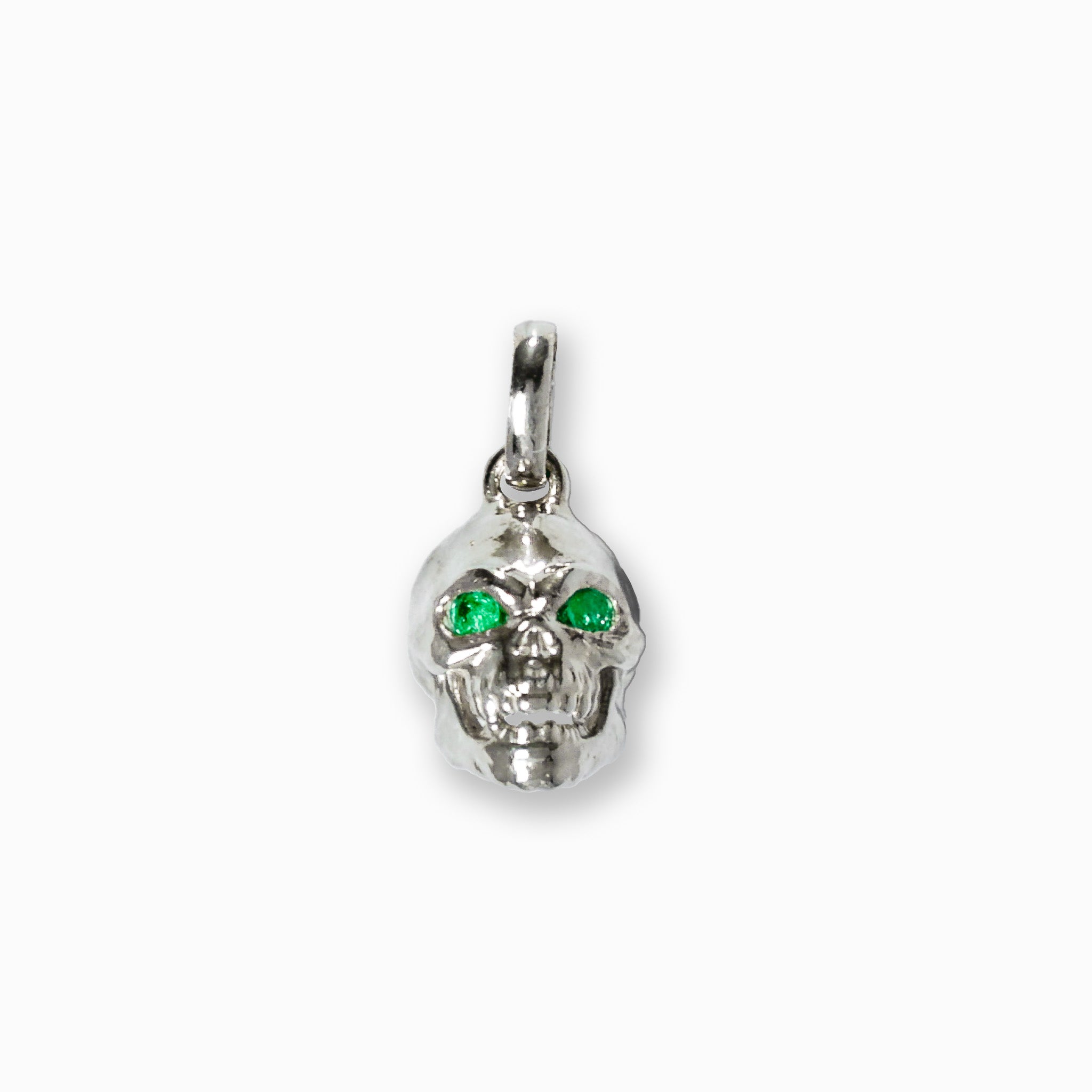 Dije tridimensional de calavera en Plata Ley 925 con dos esmeraldas naturales brillantes engastadas en los ojos.