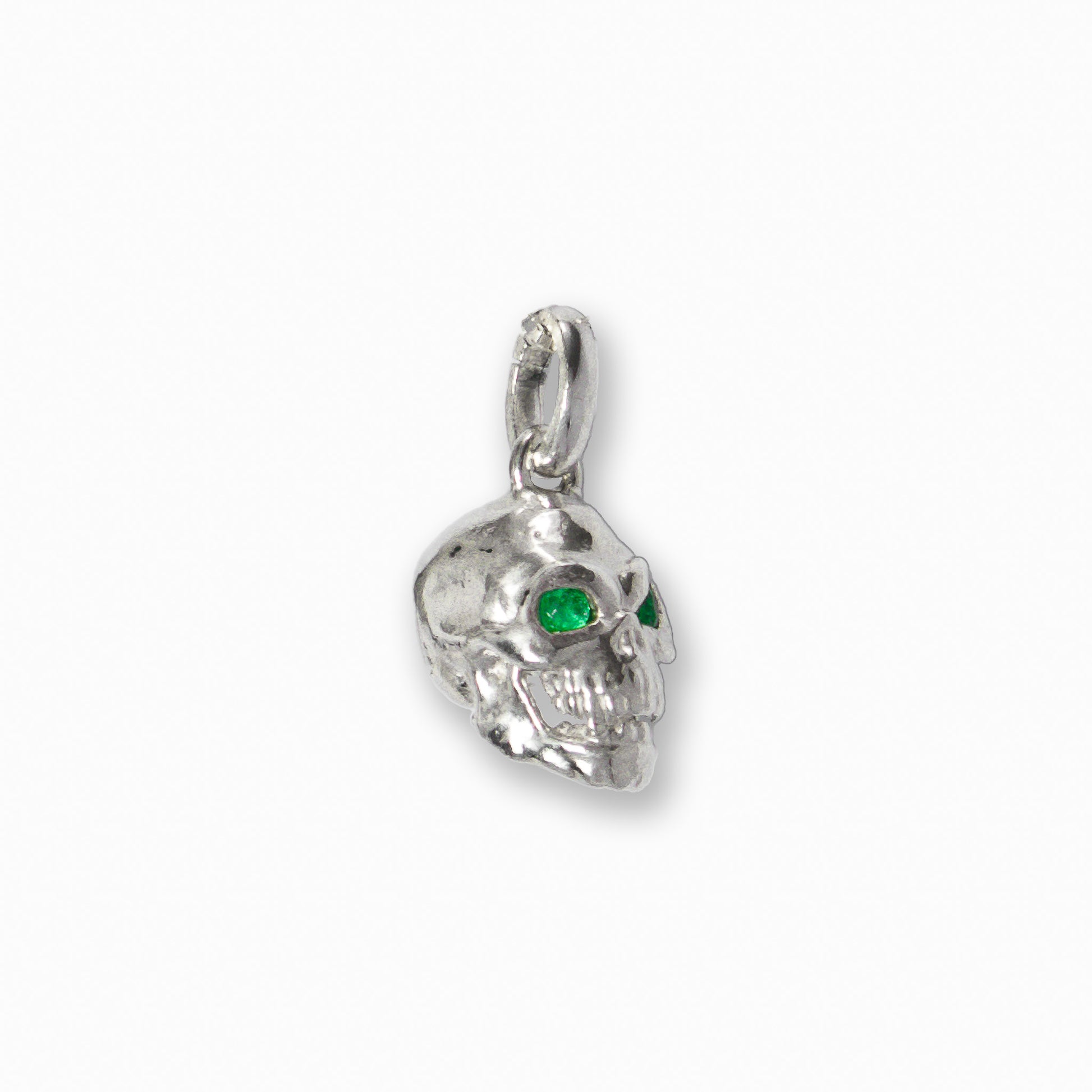 Dije tridimensional de calavera en Plata Ley 925 con dos esmeraldas naturales brillantes engastadas en los ojos.