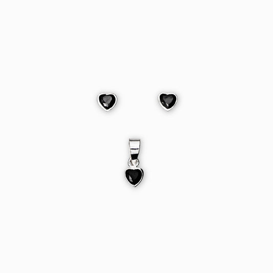 Juego de joyería en plata ley 925 que incluye aretes de topo y dije en forma de corazón con circón negro de 5 mm sobre fondo blanco.
