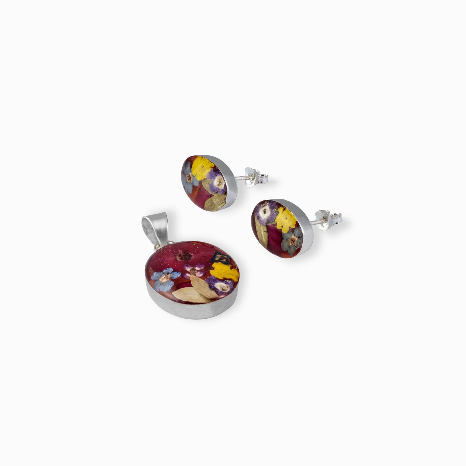 Juego de joyería en plata ley 925 con diseño de flores artísticas detalladas, incluye aretes de topo y dije sobre fondo blanco.

