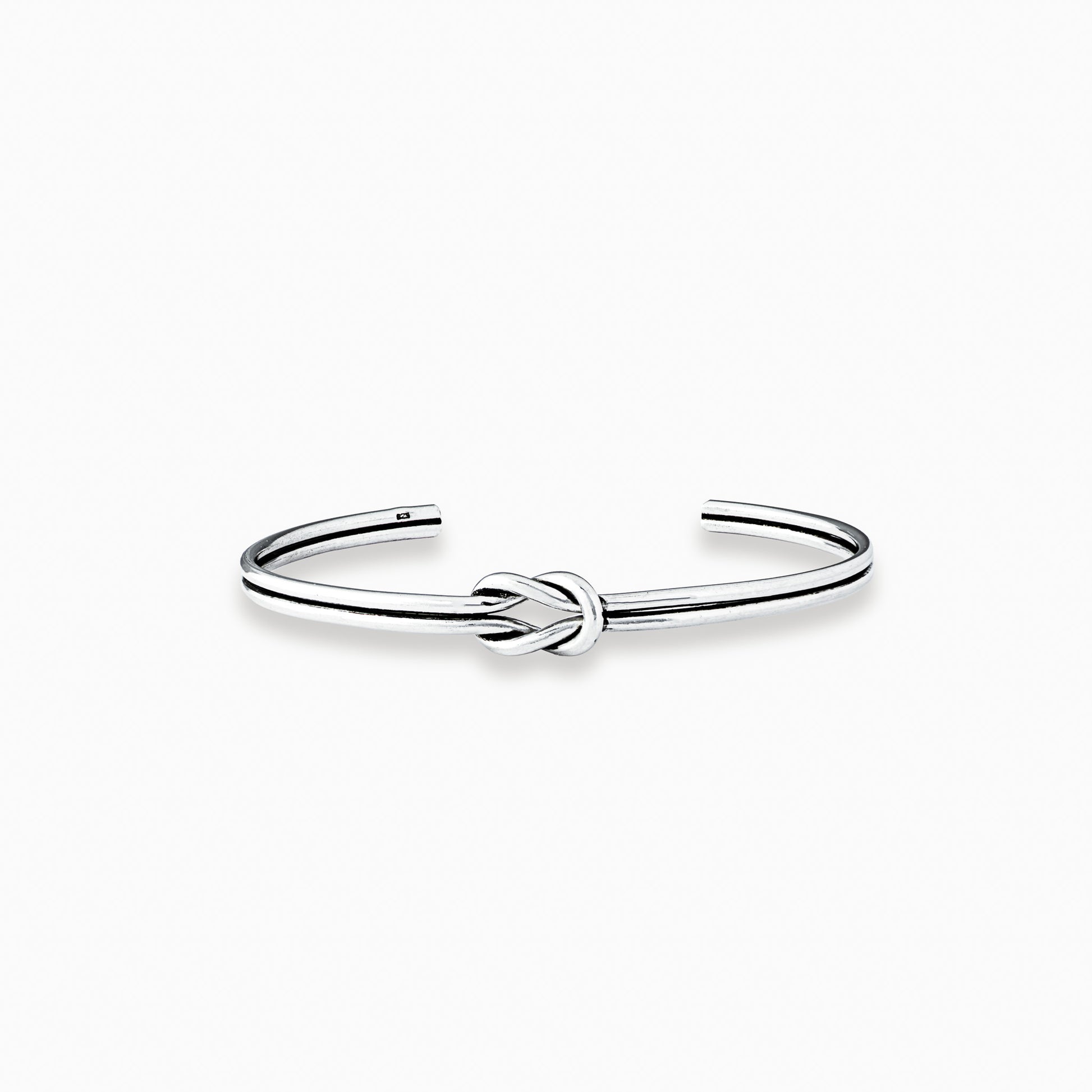 Pulsera rígida tipo aro con detalle de nudo central elaborada en plata ley 925 de 4 mm de grosor sobre fondo blanco.
