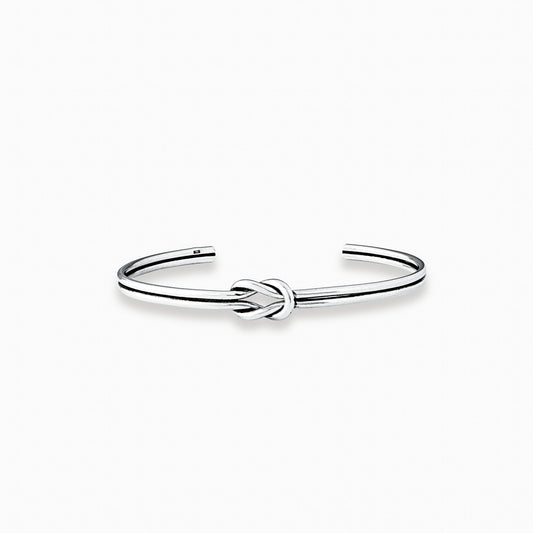 Pulsera rígida tipo aro con detalle de nudo central elaborada en plata ley 925 de 4 mm de grosor sobre fondo blanco.
