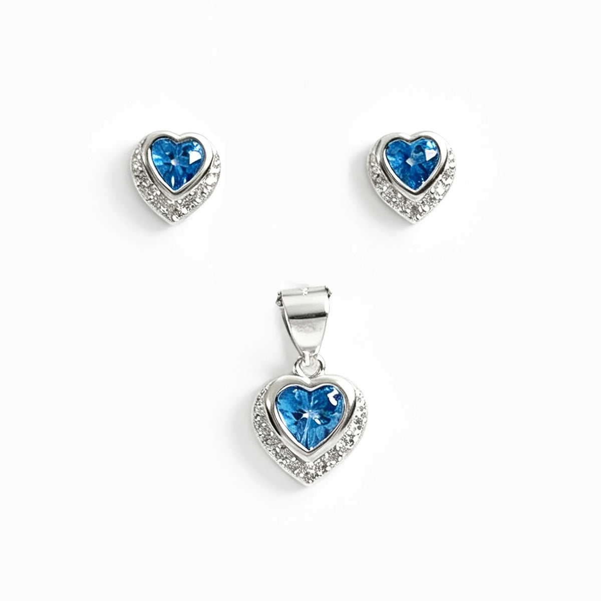 Set de topos y dije con forma de corazón en plata ley 925 con circones azul claro y halo brillante.