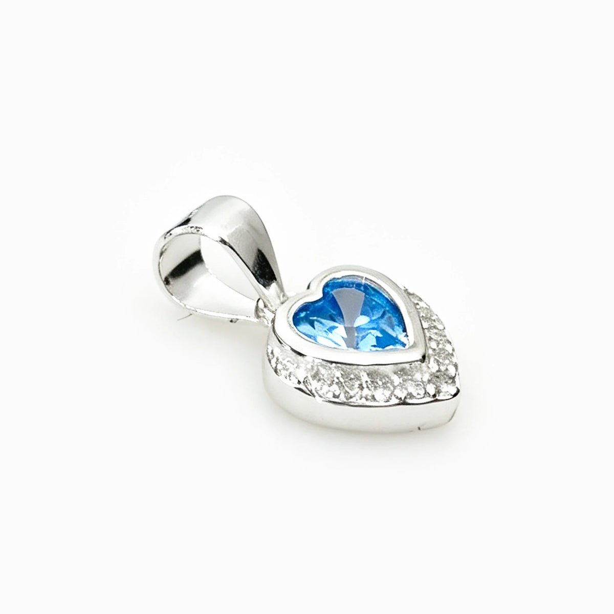 Set de topos y dije con forma de corazón en plata ley 925 con circones azul claro y halo brillante.