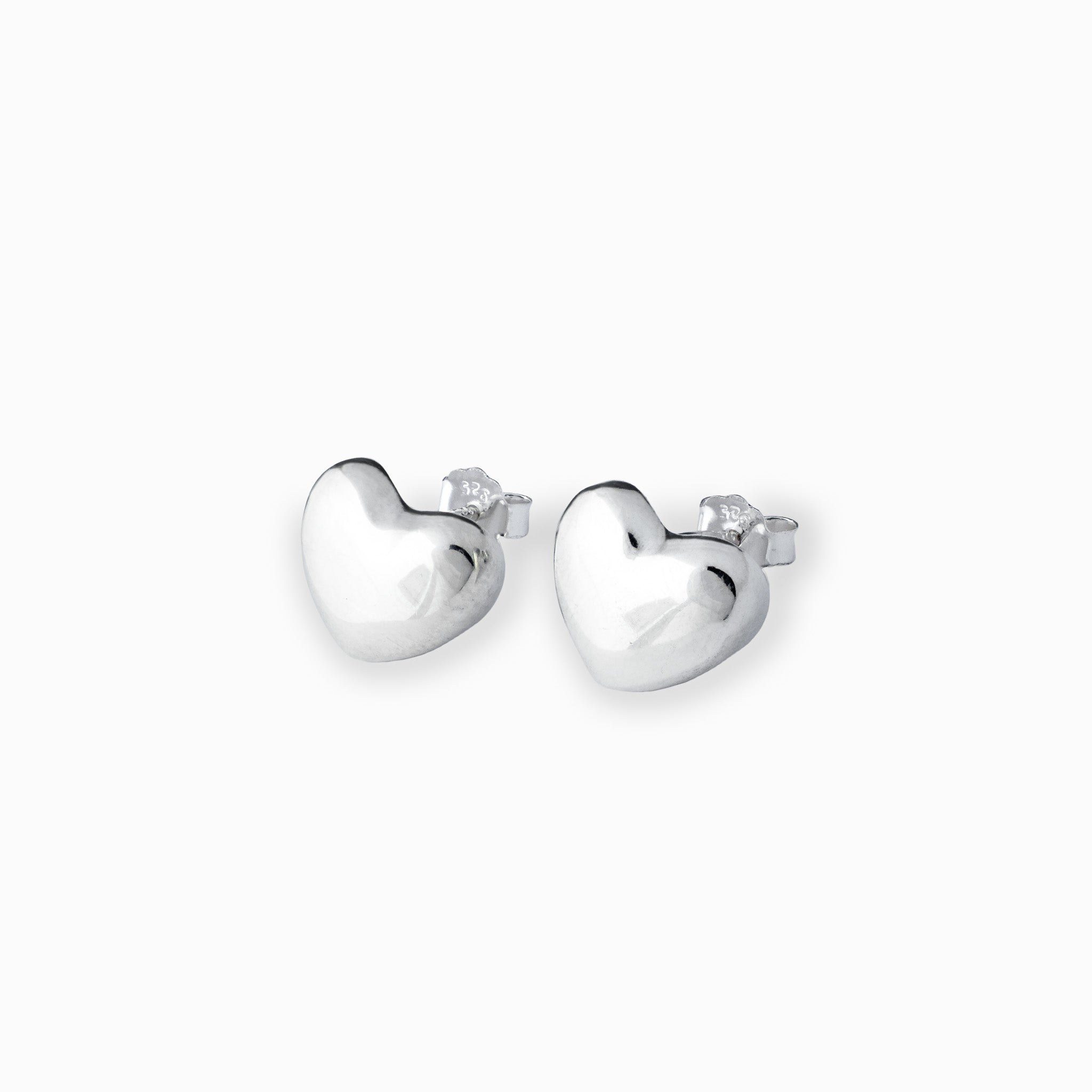 Par de aretes tipo topo con forma de corazón liso y brillante elaborados en plata ley 925 de 12 mm de ancho sobre fondo blanco.
