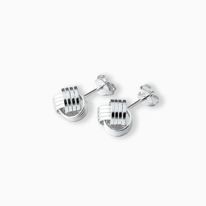 Par de aretes tipo topo con diseño de líneas entrelazadas y volumen esférico elaborados en plata ley 925 de 18 mm sobre fondo blanco.