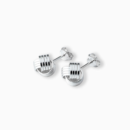 Par de aretes tipo topo con diseño de líneas entrelazadas y volumen esférico elaborados en plata ley 925 de 18 mm sobre fondo blanco.