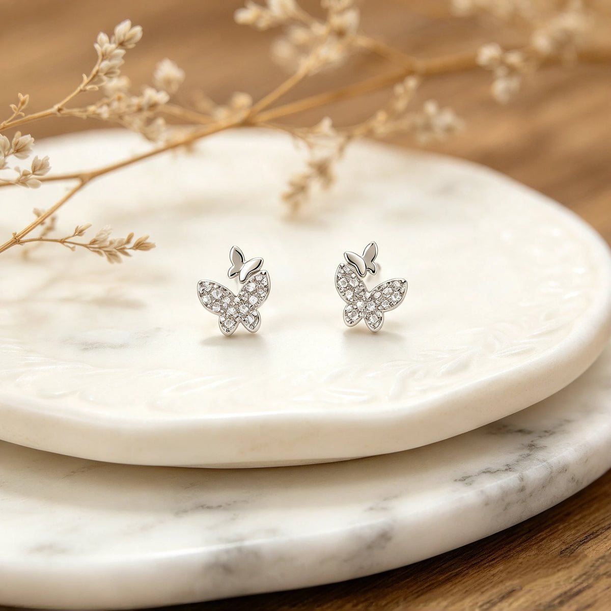 Topos con diseño asimétrico de mariposas de 8x7 mm en plata ley 925 con circones blancos