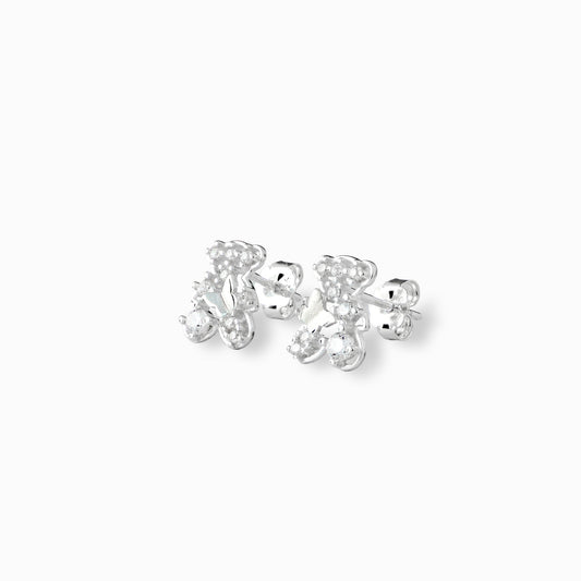 Par de aretes tipo topo con forma de osito y circón transparente central elaborados en plata ley 925 de 10 mm de alto sobre fondo blanco.
